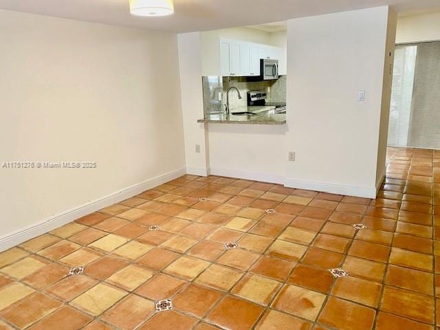 empty room featuring tile patterned flooring, a sink, and baseboards