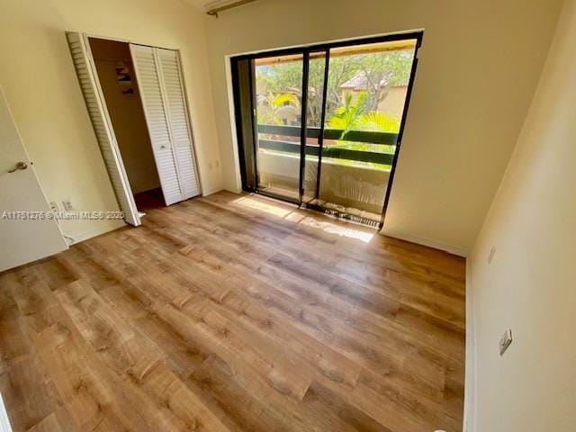 unfurnished bedroom featuring a closet, light wood-style flooring, and access to exterior