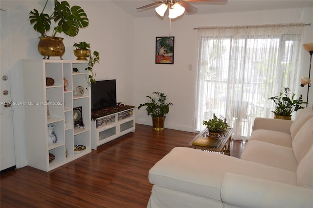 living room with dark wood-style flooring, a ceiling fan, and baseboards