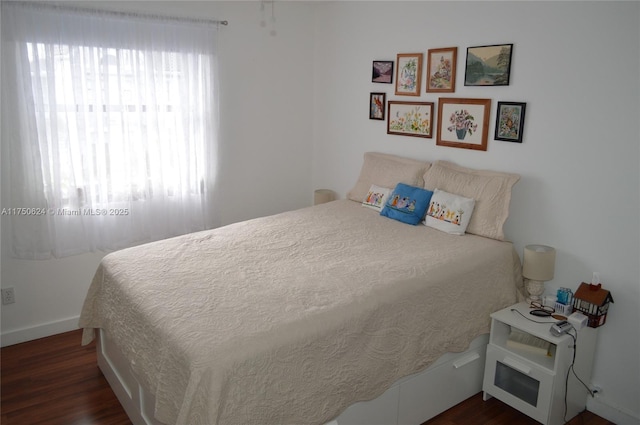 bedroom with baseboards and dark wood-type flooring