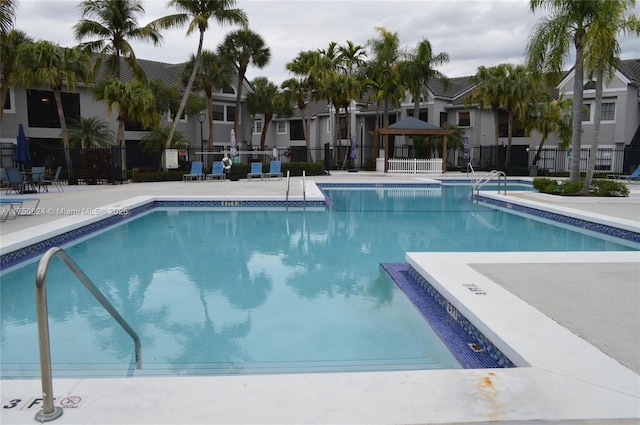 pool featuring a gazebo, a patio area, fence, and a residential view