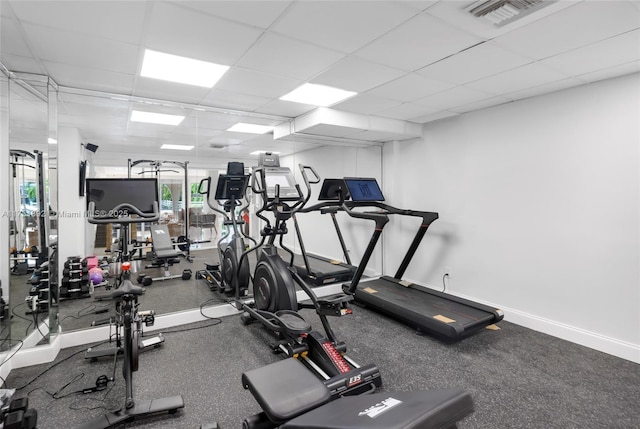 exercise room with baseboards, visible vents, and a drop ceiling