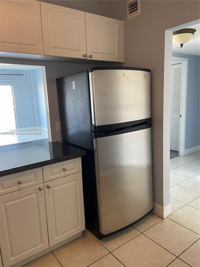 kitchen featuring visible vents, white cabinets, dark countertops, freestanding refrigerator, and light tile patterned flooring