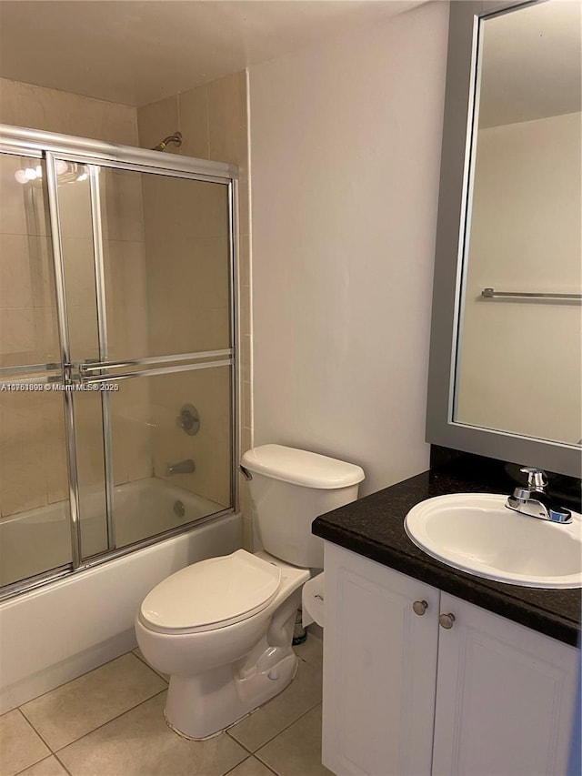 bathroom with enclosed tub / shower combo, vanity, toilet, and tile patterned floors