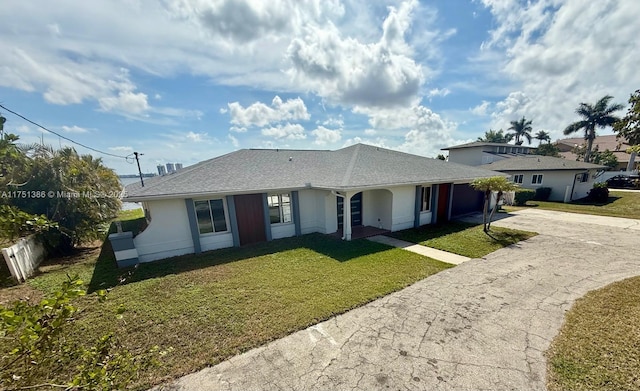 ranch-style house featuring concrete driveway, an attached garage, a front lawn, and fence