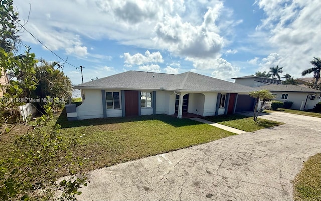 ranch-style house with a garage, a front yard, concrete driveway, and stucco siding