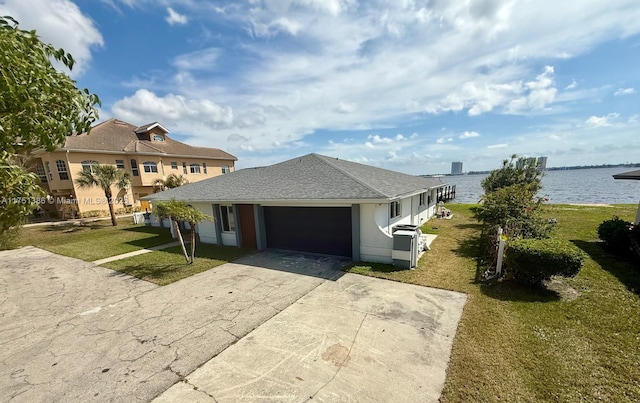 view of front of home with concrete driveway, a water view, an attached garage, and a front lawn