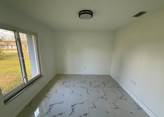 unfurnished room with marble finish floor, baseboards, visible vents, and a wealth of natural light