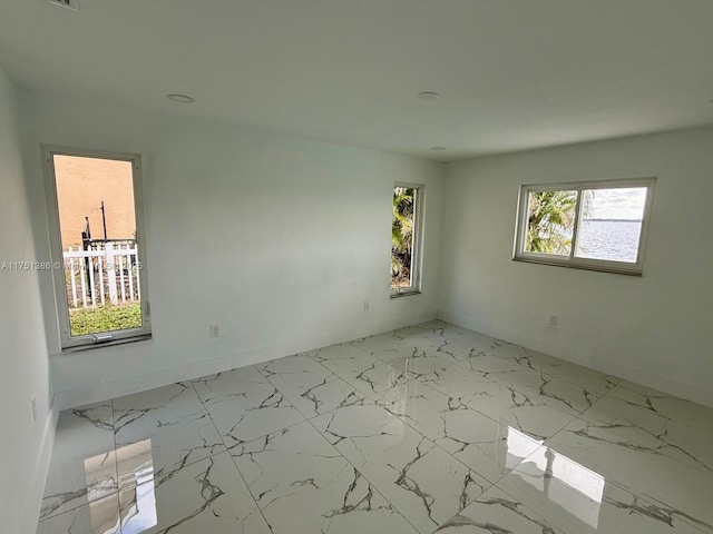 spare room with marble finish floor, visible vents, and baseboards