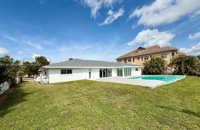 rear view of property featuring a patio, a lawn, stucco siding, and an outdoor pool