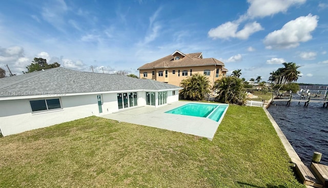 rear view of property with a yard, a patio, a shingled roof, a water view, and an outdoor pool