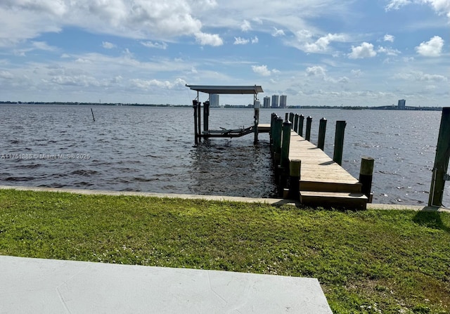 view of dock featuring a water view, a yard, and boat lift