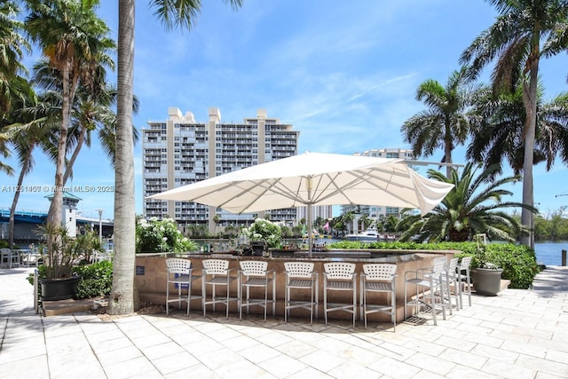 view of patio / terrace with outdoor dry bar, a water view, and a view of city