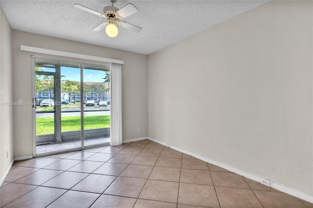 empty room with ceiling fan, a textured ceiling, baseboards, and light tile patterned floors