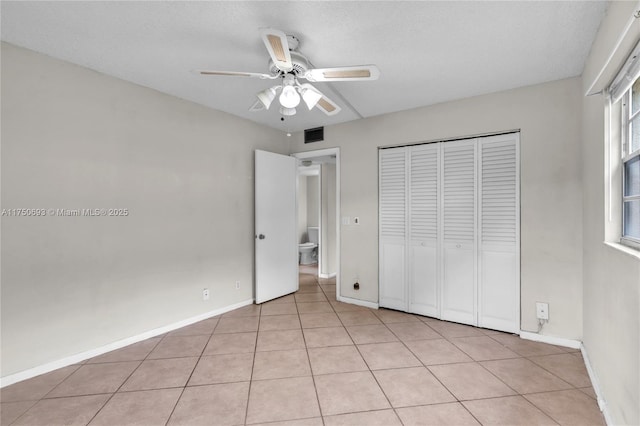 unfurnished bedroom featuring a closet, visible vents, baseboards, and light tile patterned floors