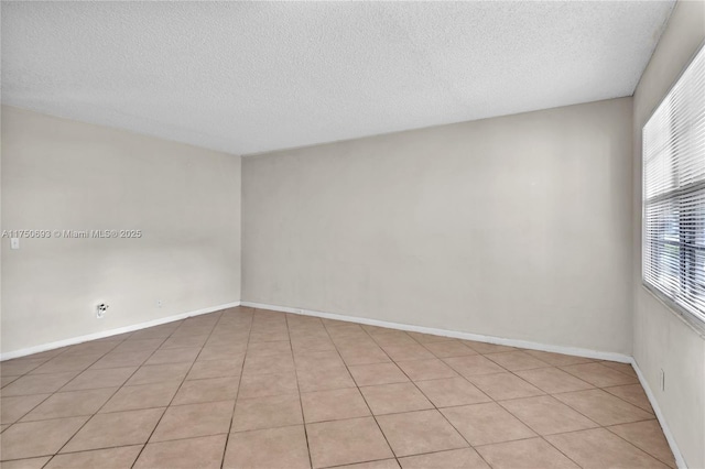 unfurnished room with baseboards and a textured ceiling