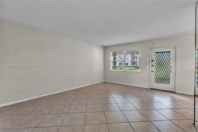 unfurnished room featuring light tile patterned floors, baseboards, and a textured ceiling