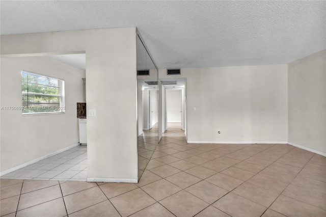 unfurnished room featuring visible vents, a textured ceiling, and light tile patterned flooring