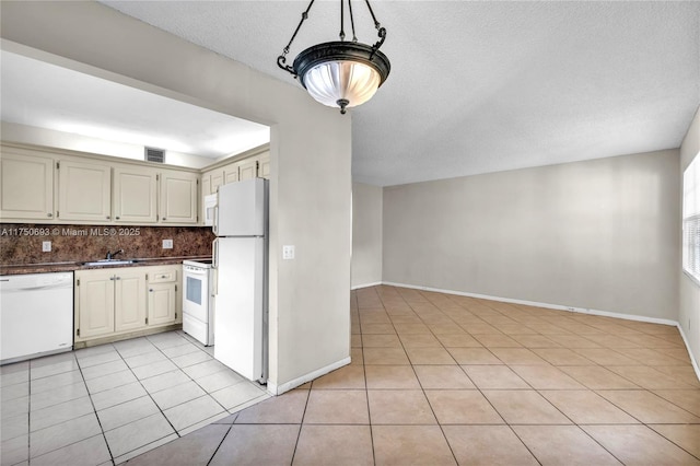 kitchen featuring light tile patterned floors, dark countertops, visible vents, backsplash, and white appliances