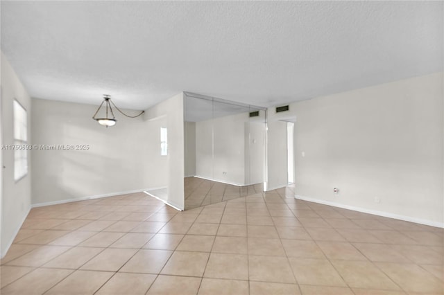 spare room featuring visible vents, a textured ceiling, and light tile patterned floors