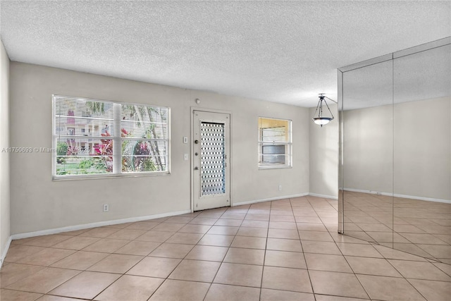 interior space with light tile patterned floors, baseboards, and a textured ceiling