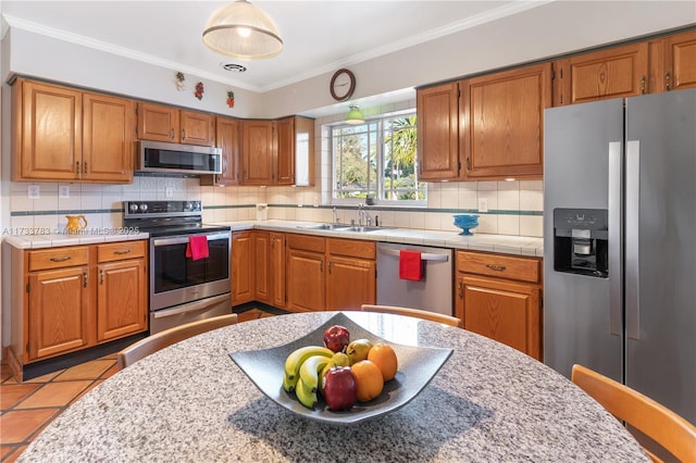 kitchen featuring stainless steel appliances, brown cabinets, and light countertops