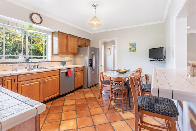 kitchen with tile countertops, stainless steel appliances, hanging light fixtures, backsplash, and a sink