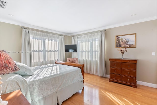 bedroom featuring light wood finished floors, ornamental molding, and multiple windows