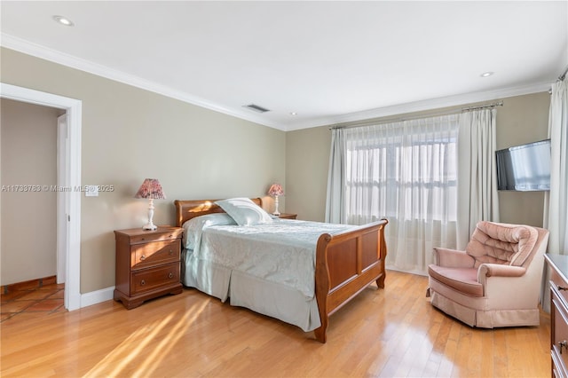 bedroom with light wood-style floors, visible vents, ornamental molding, and baseboards