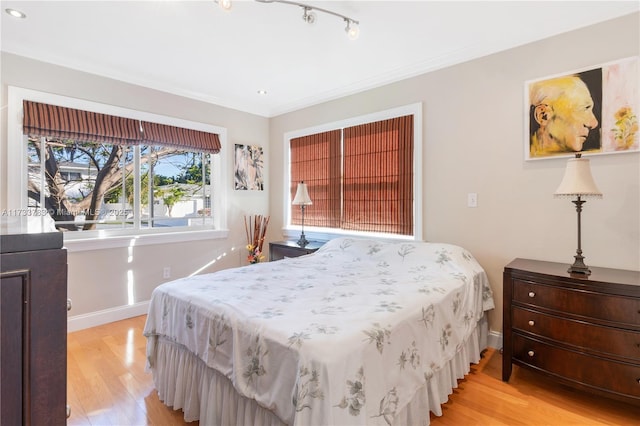 bedroom with baseboards, light wood-style flooring, and crown molding