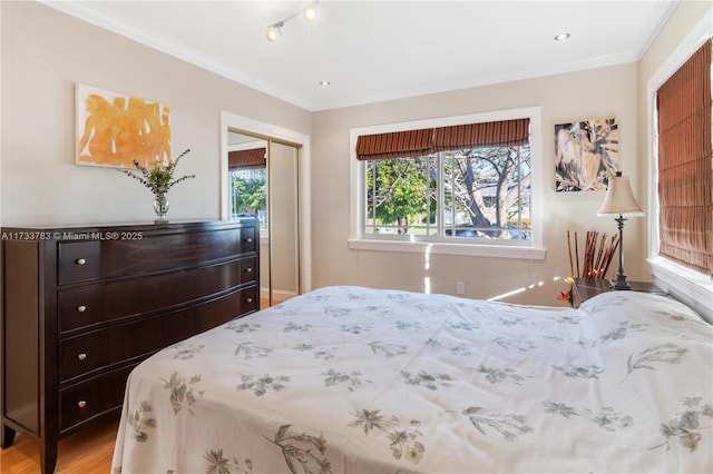 bedroom featuring light wood-type flooring, a closet, and crown molding