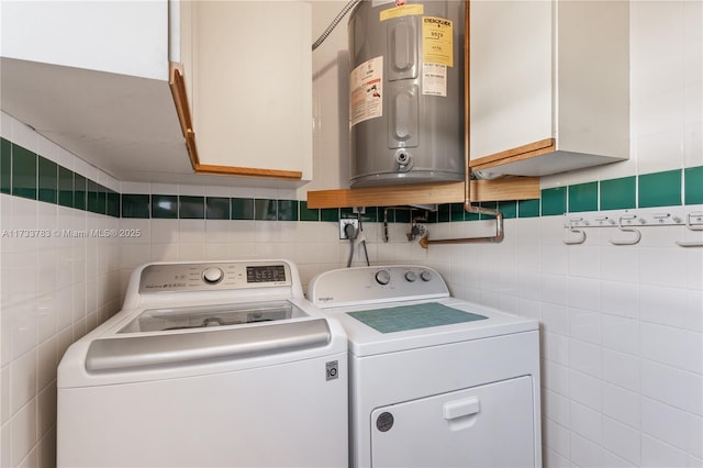 washroom with washing machine and dryer, cabinet space, tile walls, and water heater