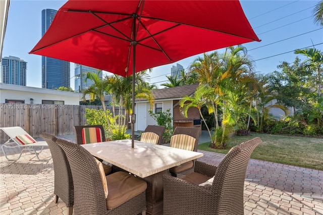 view of patio / terrace with outdoor dining space, fence, and a city view