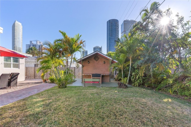 view of yard with a patio, fence, and a city view