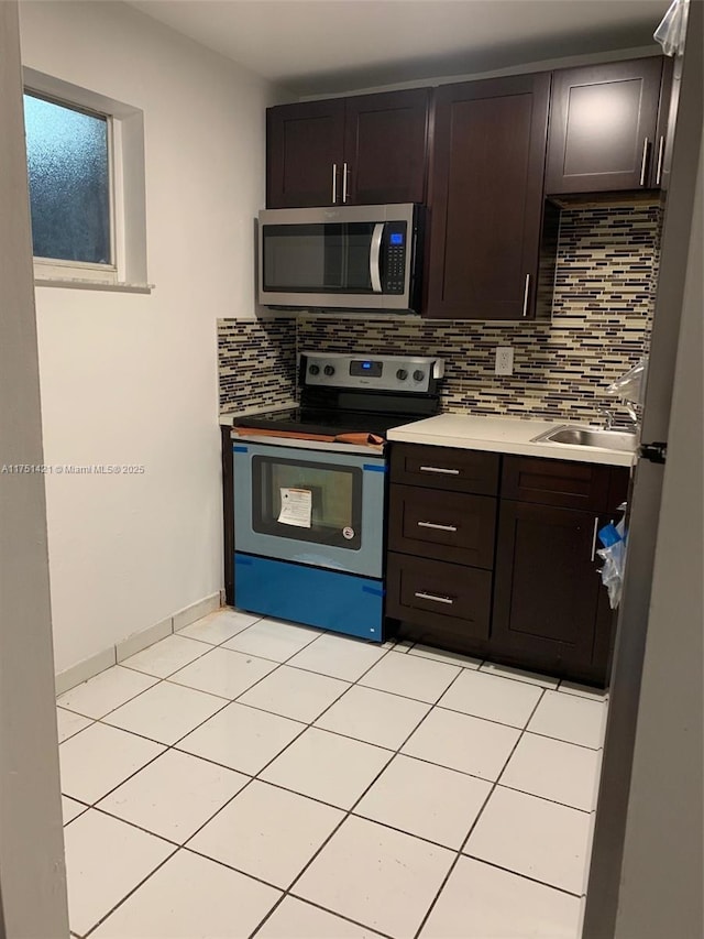 kitchen with stainless steel appliances, light countertops, a sink, and dark brown cabinetry