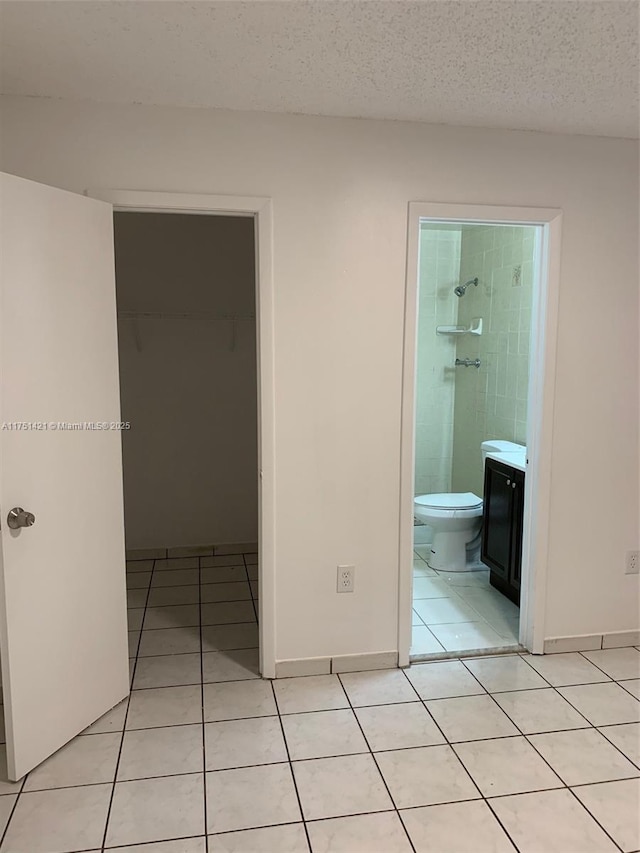 interior space featuring light tile patterned floors, a textured ceiling, and baseboards