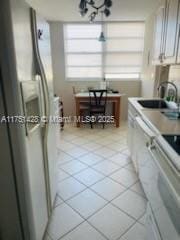 kitchen with white cabinets, stove, freestanding refrigerator, light countertops, and a sink