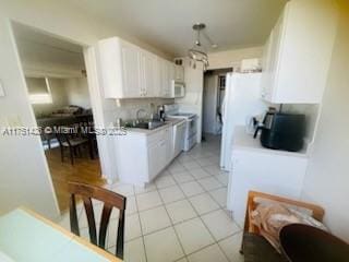 kitchen featuring light countertops, white microwave, stove, light tile patterned flooring, and white cabinets