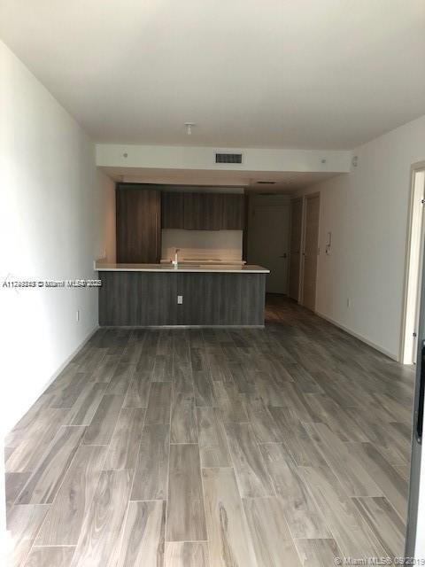 unfurnished living room featuring wood finished floors and visible vents