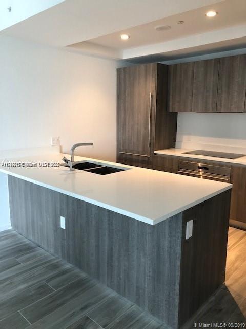 kitchen with light wood-style flooring, black electric cooktop, light countertops, a sink, and recessed lighting