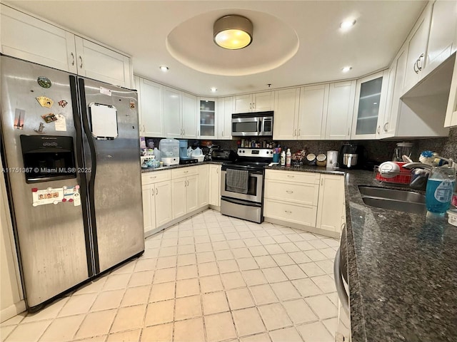 kitchen with white cabinets, a tray ceiling, stainless steel appliances, and a sink