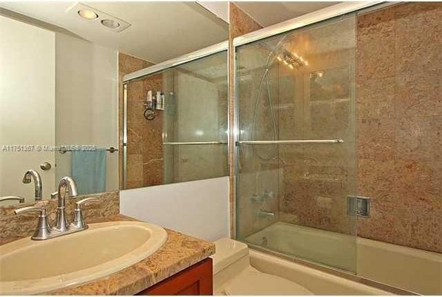 full bath featuring shower / bath combination with glass door, vanity, and toilet