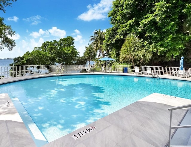 community pool with a patio area and fence