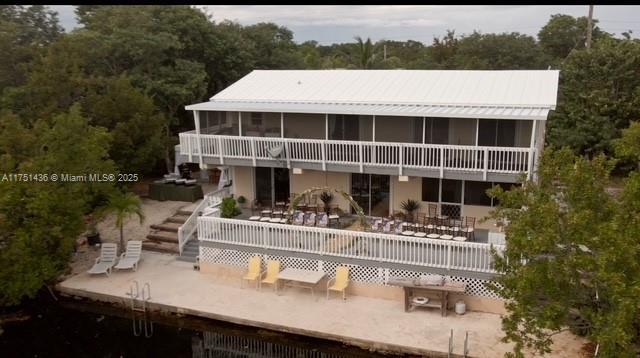 rear view of property featuring a sunroom, a patio, metal roof, and stairs