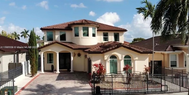 mediterranean / spanish house with stucco siding, a tile roof, and fence