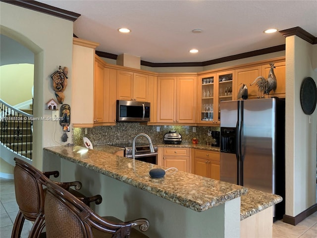 kitchen featuring backsplash, a peninsula, stainless steel appliances, and a breakfast bar area