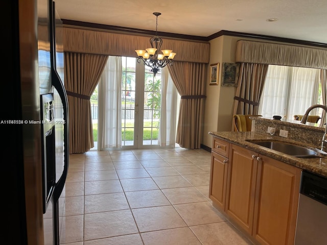 kitchen featuring a sink, dark stone countertops, stainless steel dishwasher, light tile patterned floors, and a chandelier