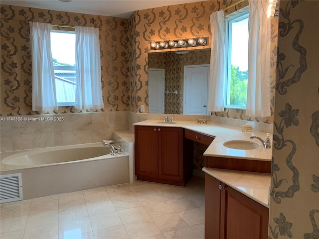 bathroom featuring visible vents, wallpapered walls, double vanity, a bath, and a sink