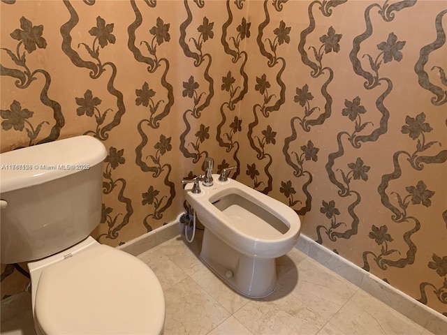 half bath featuring toilet, a bidet, and baseboards