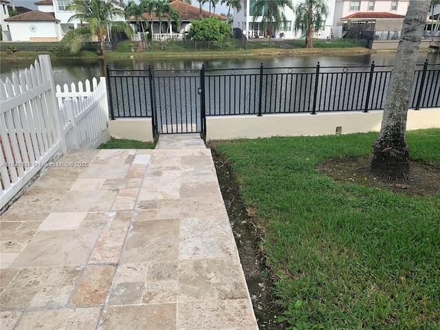 view of yard featuring a gate, a water view, and fence